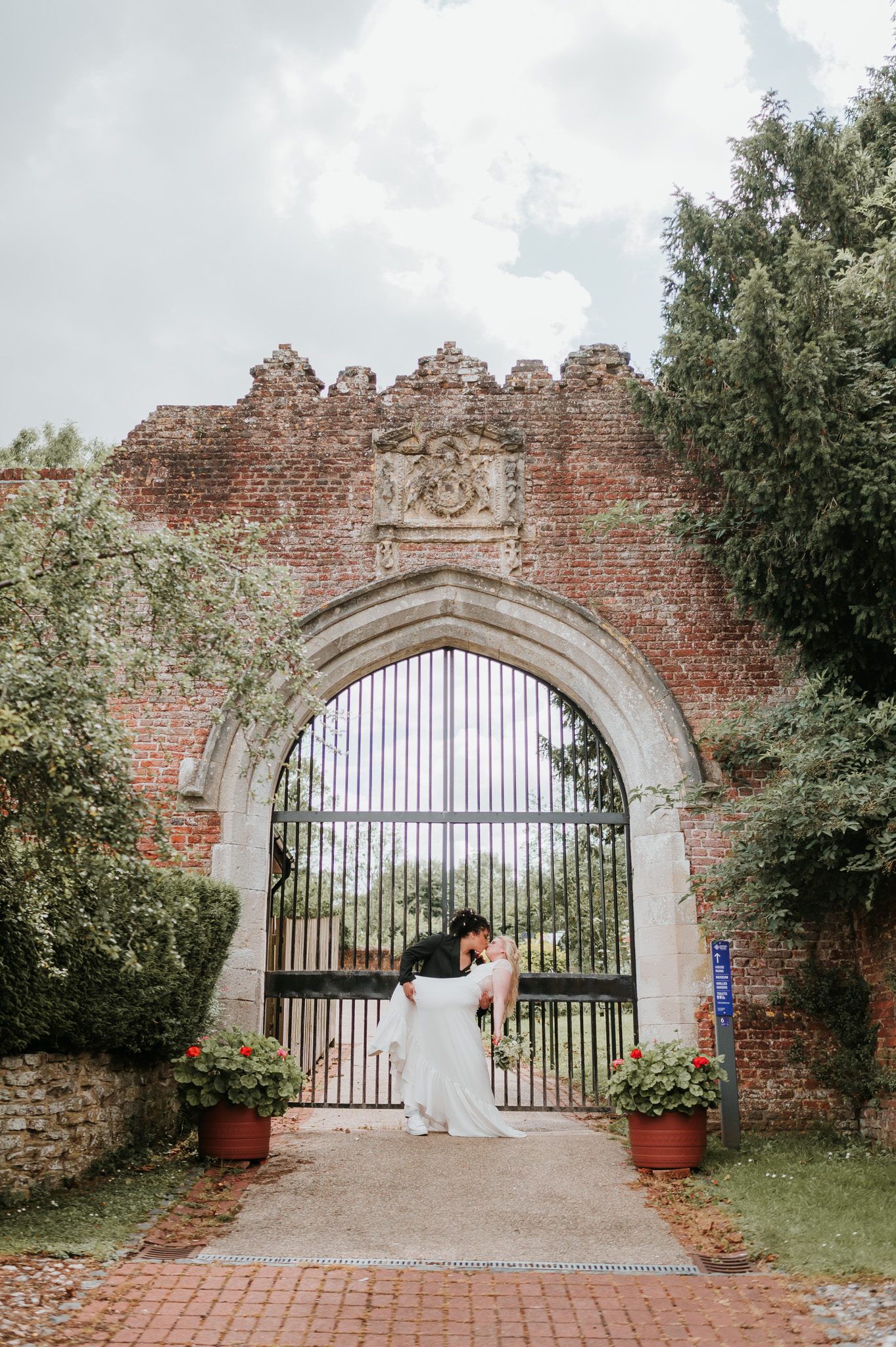 Bride and bride embracing after their wedding ceremony in front of a gate to castle ruins