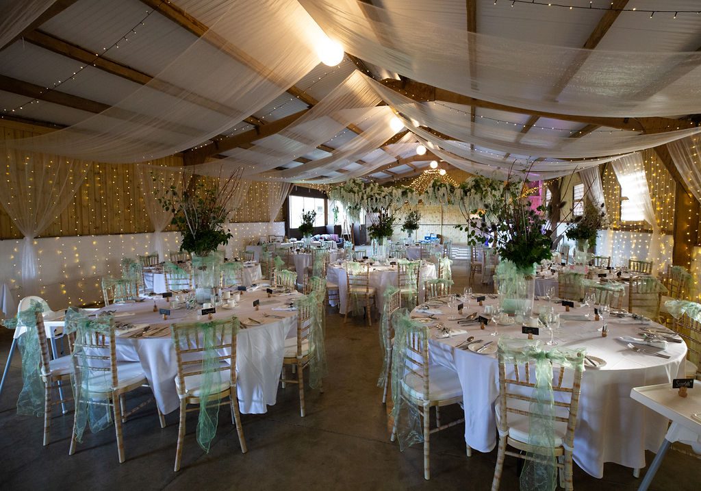 Barn set up for a wedding reception with chivari chairs and round tables