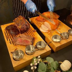 Server carving roast meats at a wedding buffet station
