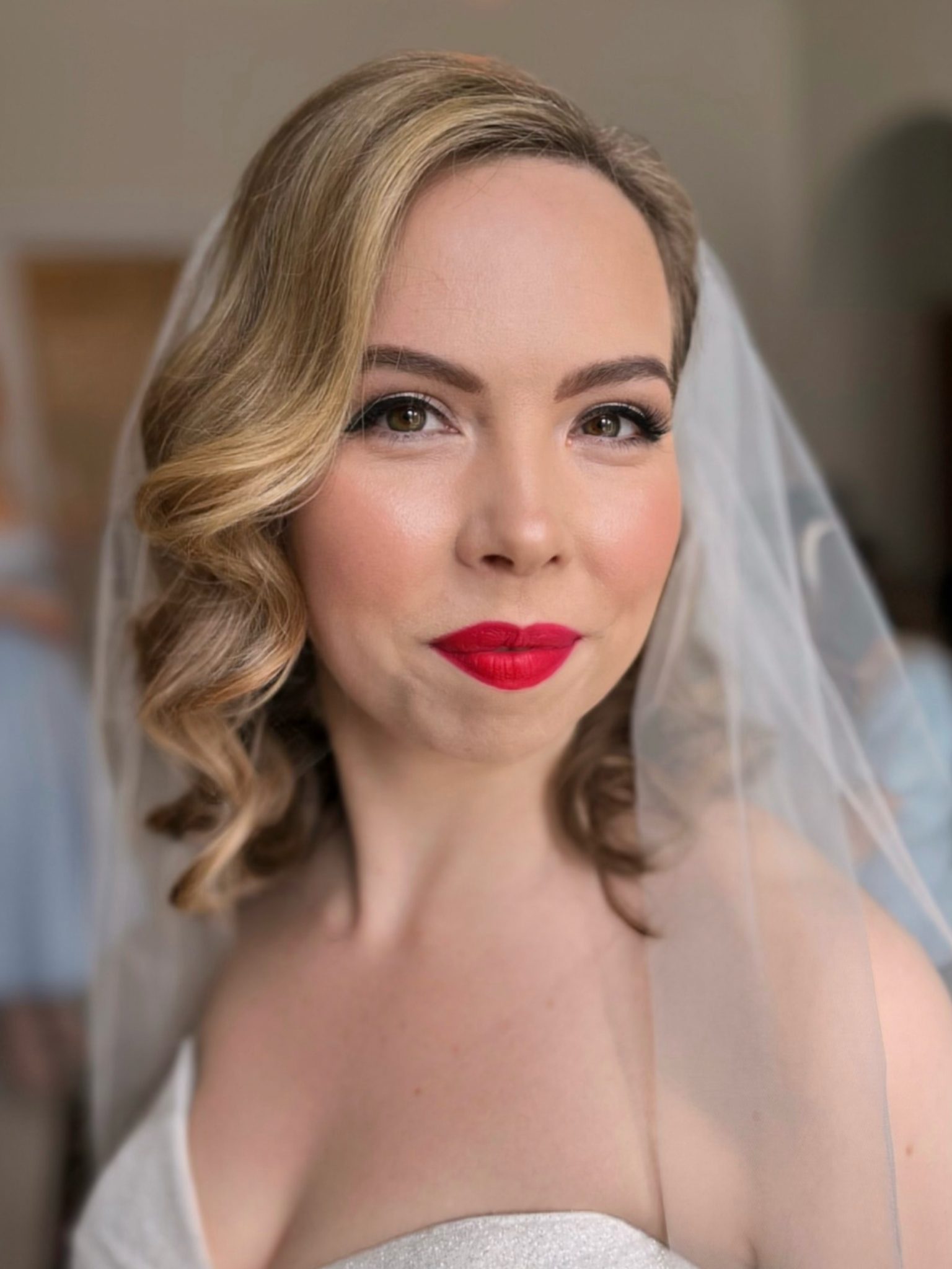 Bride styled with classic Old Hollywood waves and glamorous makeup featuring bold eyeliner, sculpted brows, and a red matte lip, evoking timeless red carpet elegance.