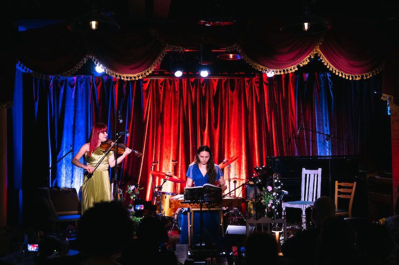 Violinist and kankles player performing together in a theatre venue.
