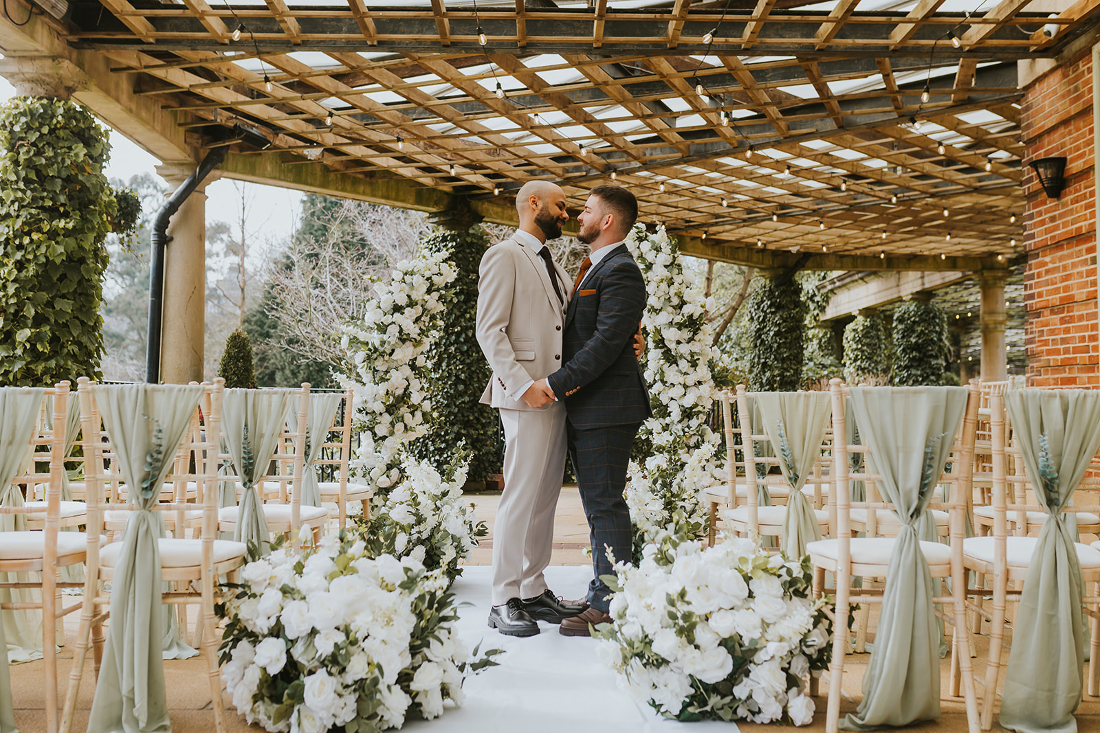 Luxury same-sex wedding styling at The Sun Pavilion by Love Stories Events featuring white floral ceremony meadows, statement wedding arch, romantic aisle flowers, sage green chair draping and elegant outdoor ceremony decor. Yorkshire wedding stylist specialising in luxury wedding decor hire, ceremony styling, floral installations and editorial wedding design for Harrogate weddings, Leeds weddings, York weddings and modern romantic wedding inspiration.