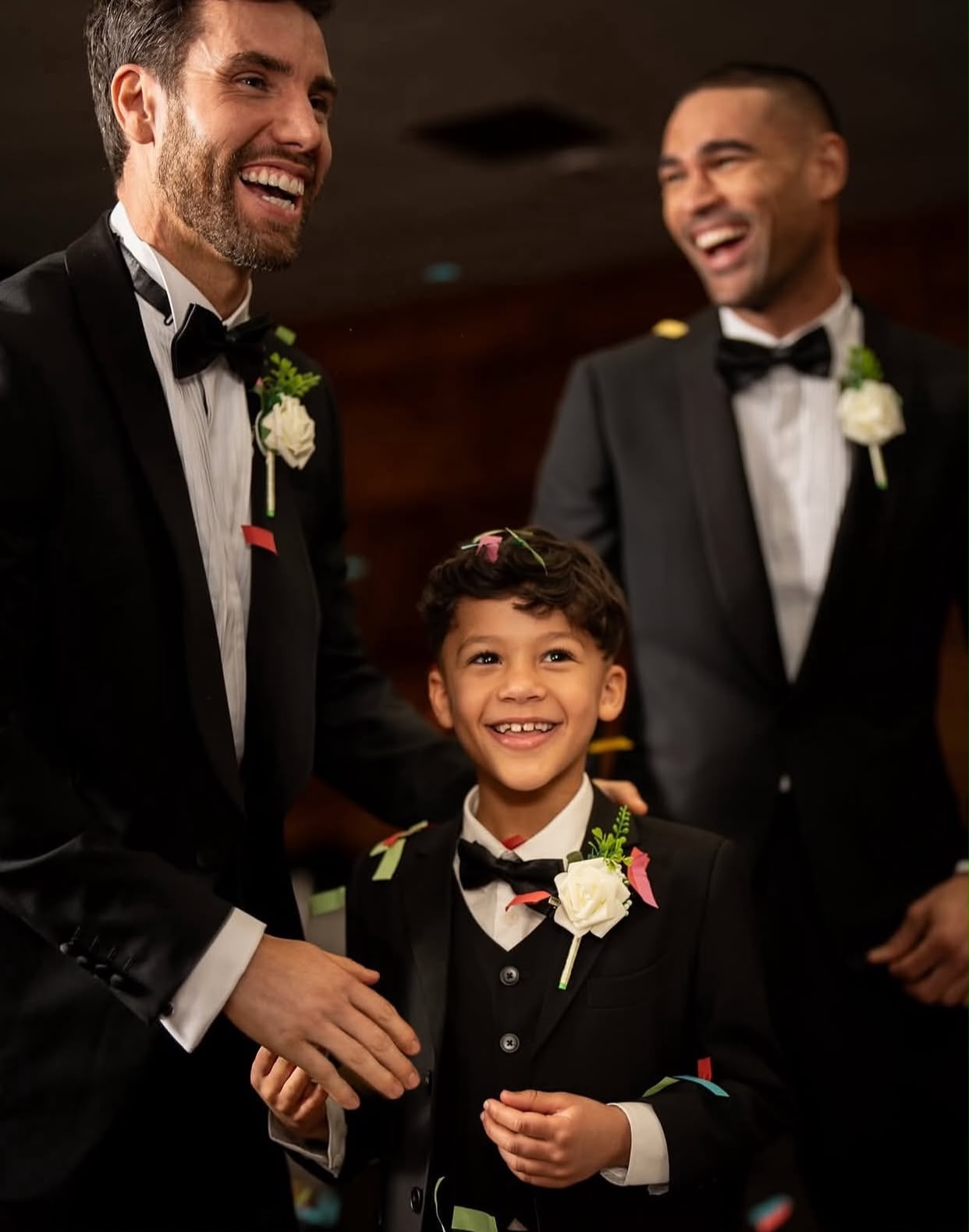 A page boy wearing a black 3-piece tuxedo matching with the groomsmen.
