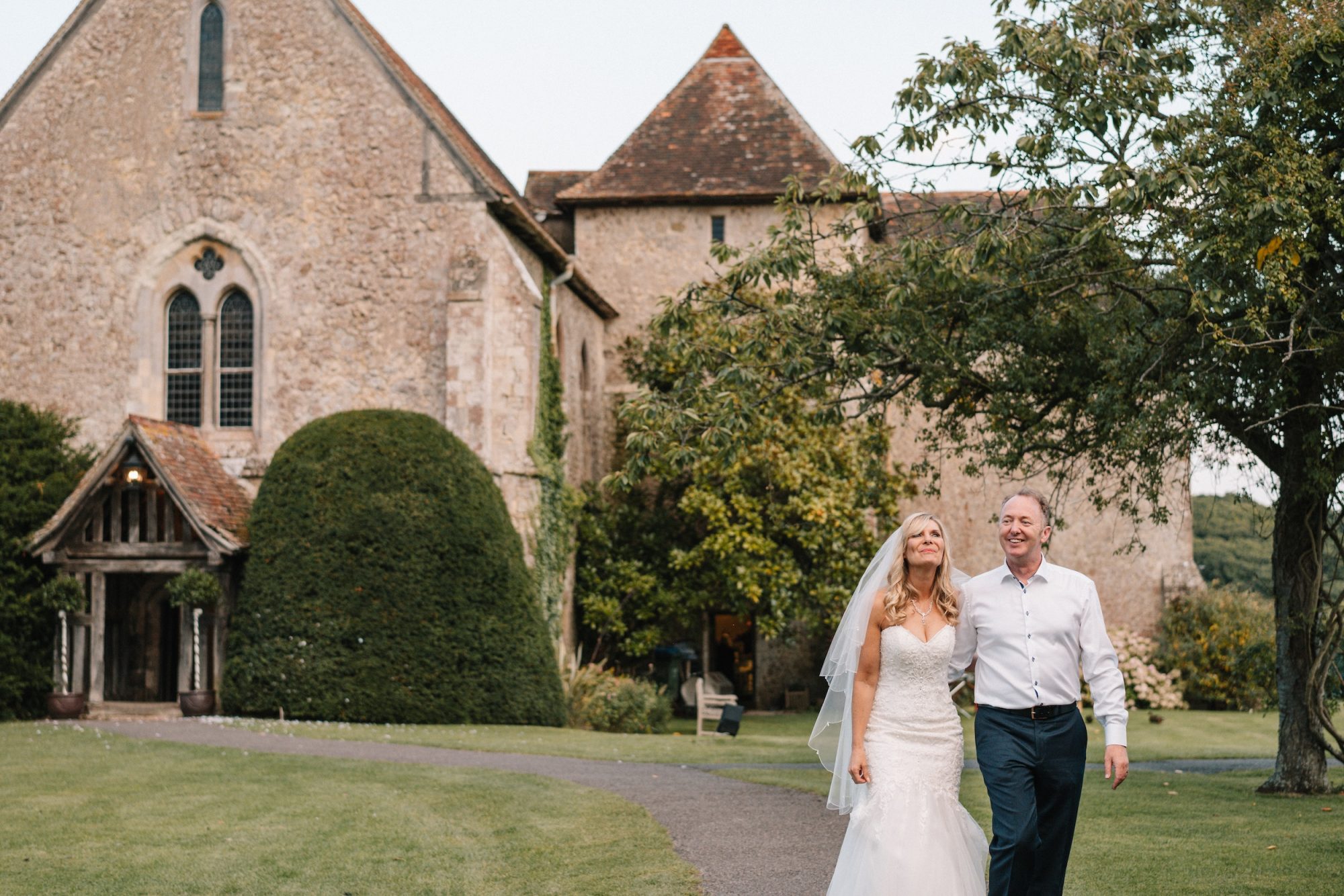 Bridal couple walking with priory background