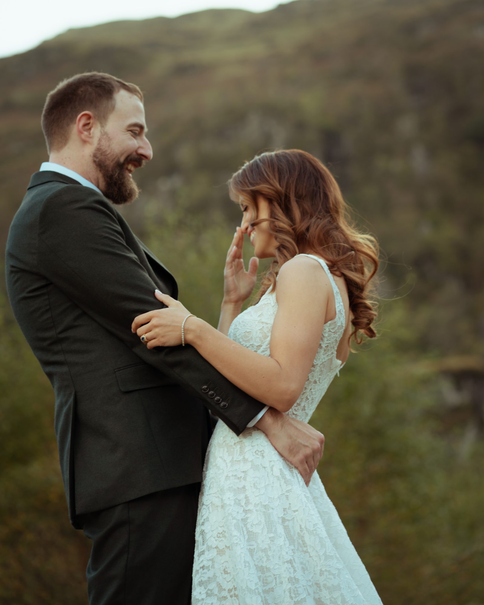 A couple laughs while holding each other in the mountains